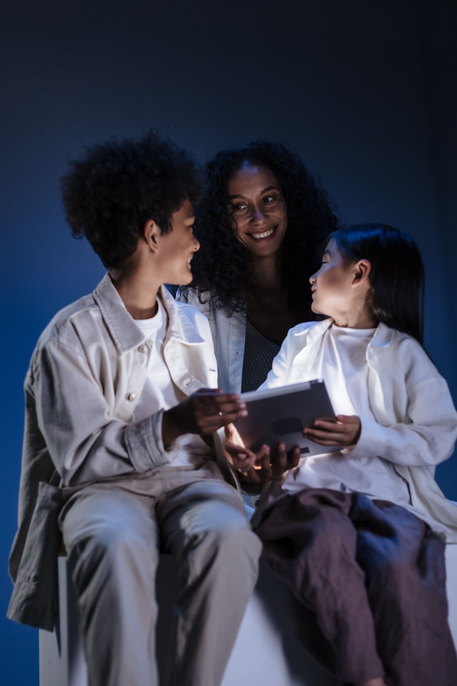 A mother smiling with her two children while looking at a tablet together